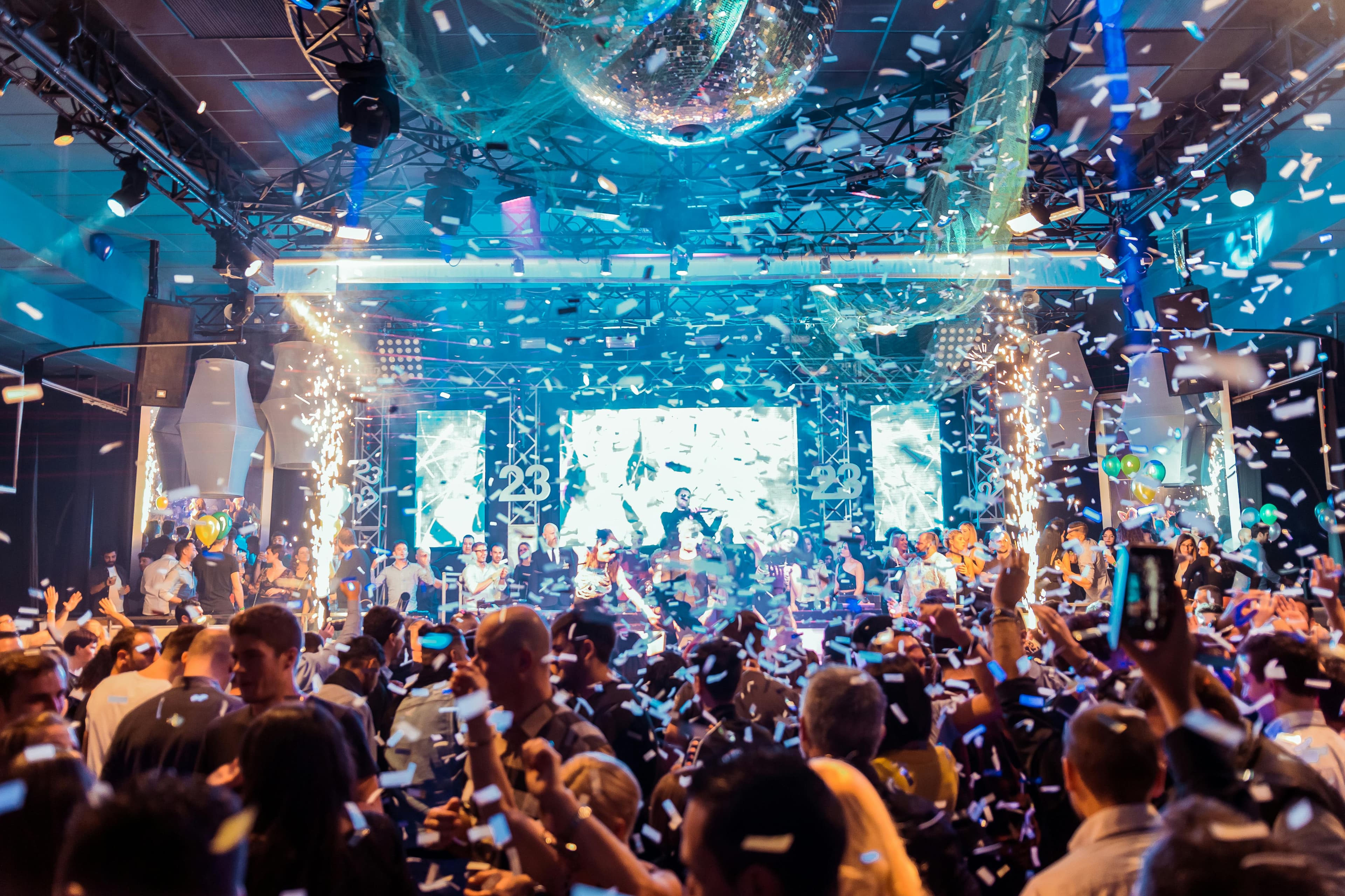 Packed dance floor with confetti, sparklers, and a disco ball at E11even Miami